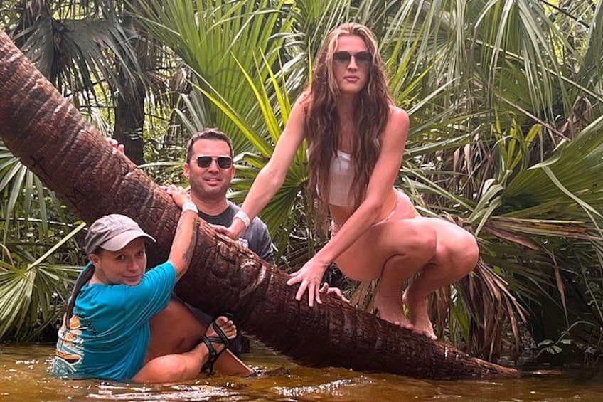 Three people interacting with a large tree trunk in a natural setting. 5