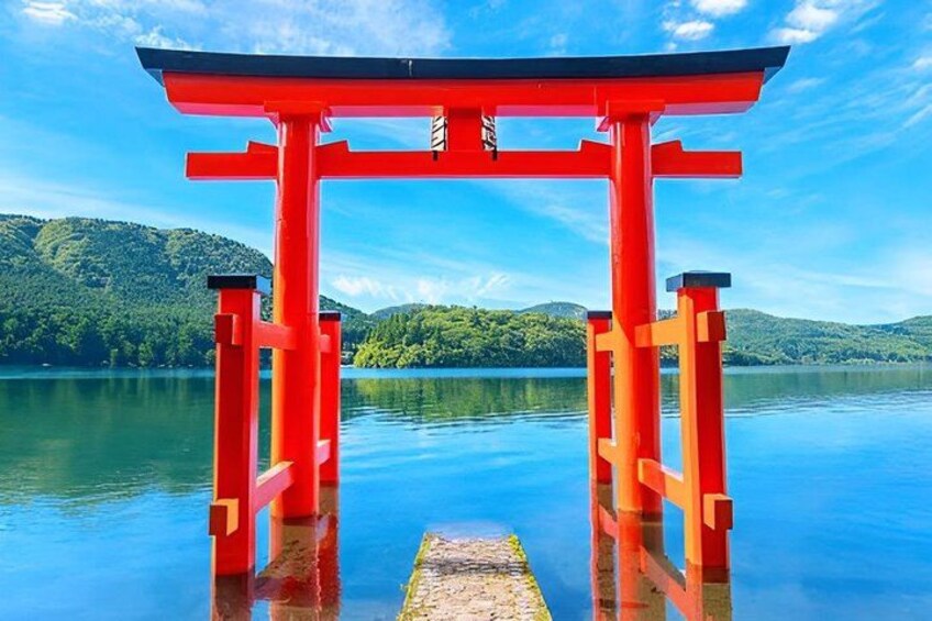 A red torii gate over a calm lake with mountains in the background. 2
