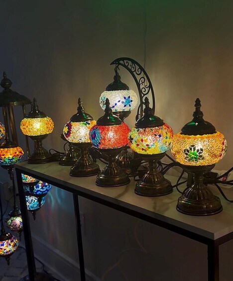 A collection of colorful, mosaic-patterned table lamps on a table. 3