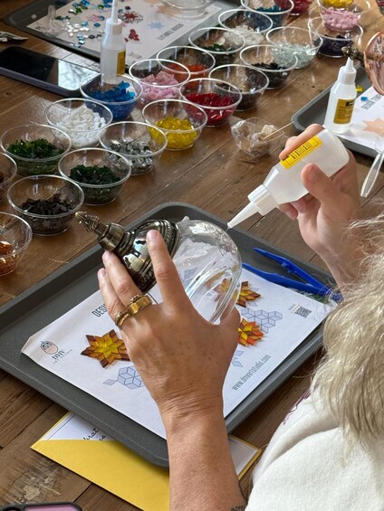 A person working on a craft project, handling a bottle and a clear plastic container. 4