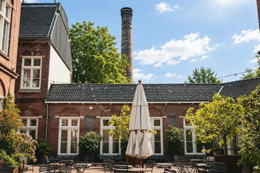 A brick building with a chimney, outdoor seating, and trees. 2