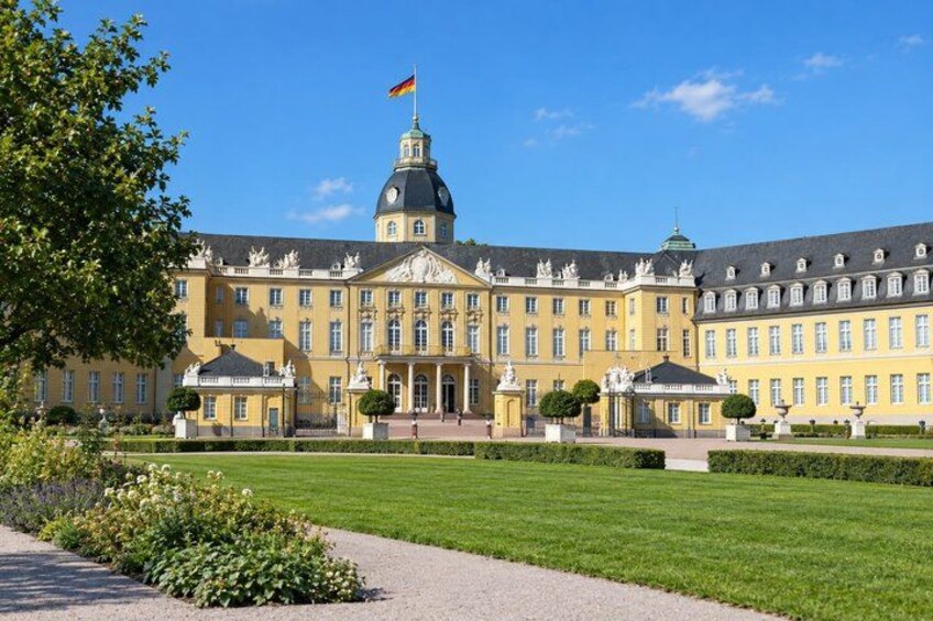 A large yellow building with a flag, surrounded by a well-manicured lawn and a clear blue sky. 5