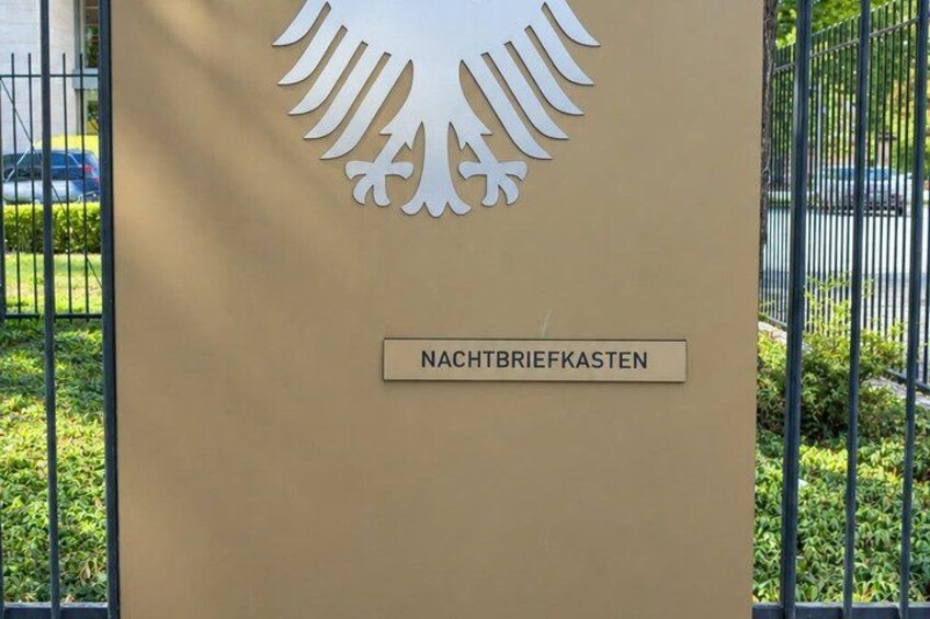 A building entrance with a large emblem and a sign reading 'NACHTBRIEFKASTEN'. 4