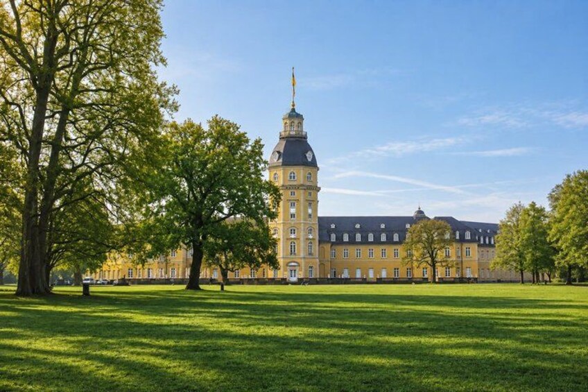 A large yellow building with a tower, surrounded by green grass and trees. 3