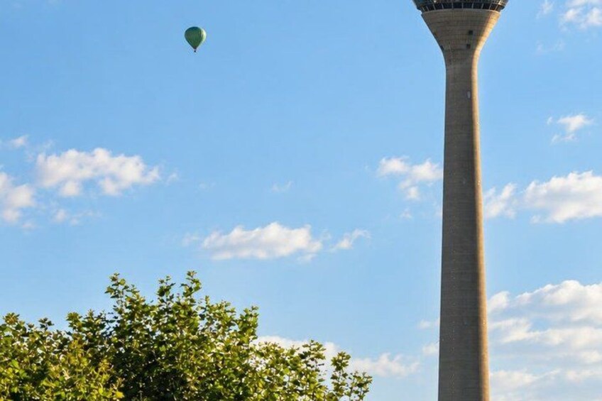 A tall tower with a balloon in the sky and trees in the foreground. 2