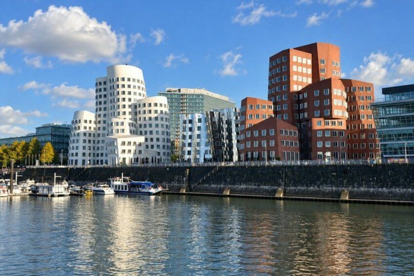 A waterfront cityscape with modern buildings, a river, and boats. 5