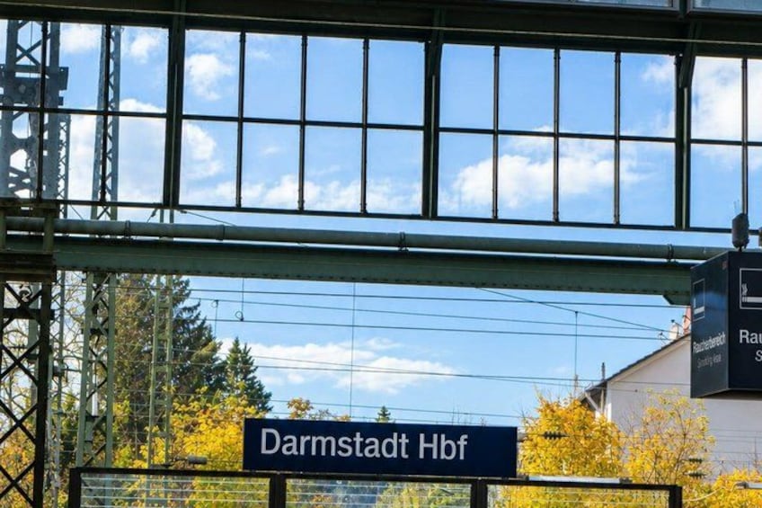 A sign for Darmstadt Hbf with a clear sky and trees in the background. 5