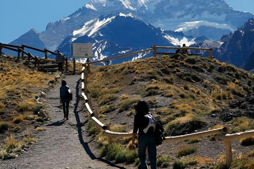 A hiking trail with wooden railings, a signpost, and a mountain with snow-capped peaks in the background. 5