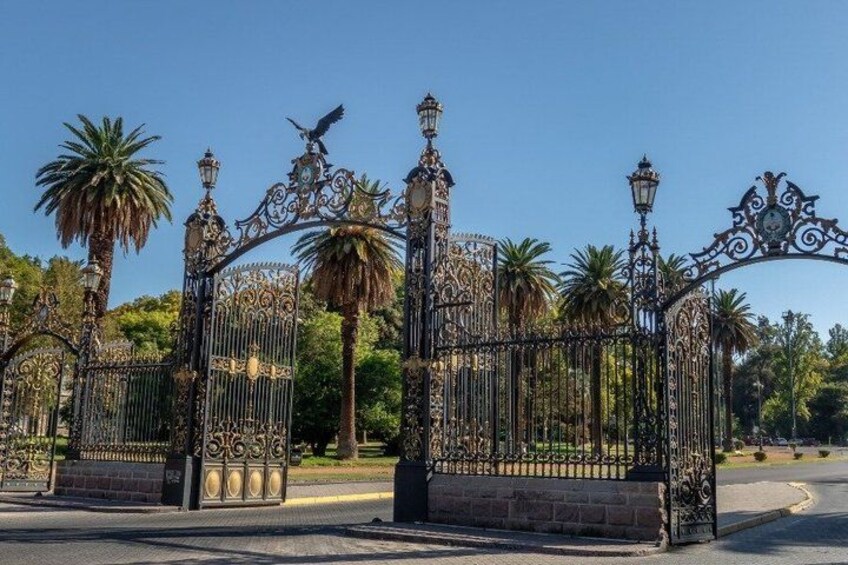 Ornate wrought iron gates with intricate designs and a bird perched on one of the posts. 2