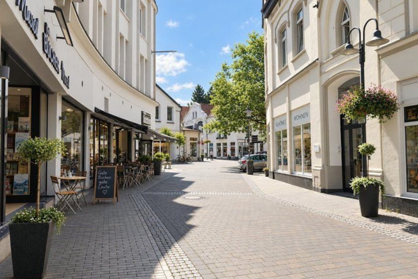A cobblestone street lined with shops and outdoor seating. 3