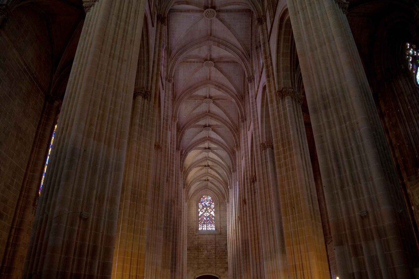 A cathedral interior with high vaulted ceilings, large columns, and a stained glass window. 3
