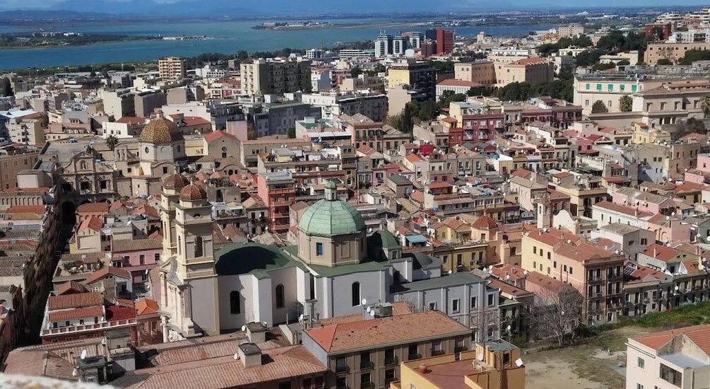 Un paisaje urbano costero con arquitectura densa, una iglesia destacada con una cúpula verde y una masa de agua al fondo. 4