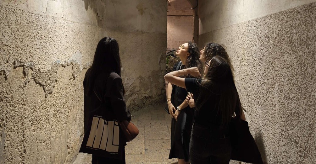 Un grupo de personas en un pasillo estrecho y tenuemente iluminado, con paredes de textura rugosa. 2