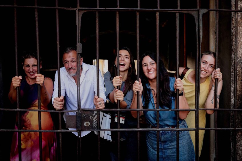 Un grupo de personas tras los barrotes, tomadas de las manos y sonriendo. 1