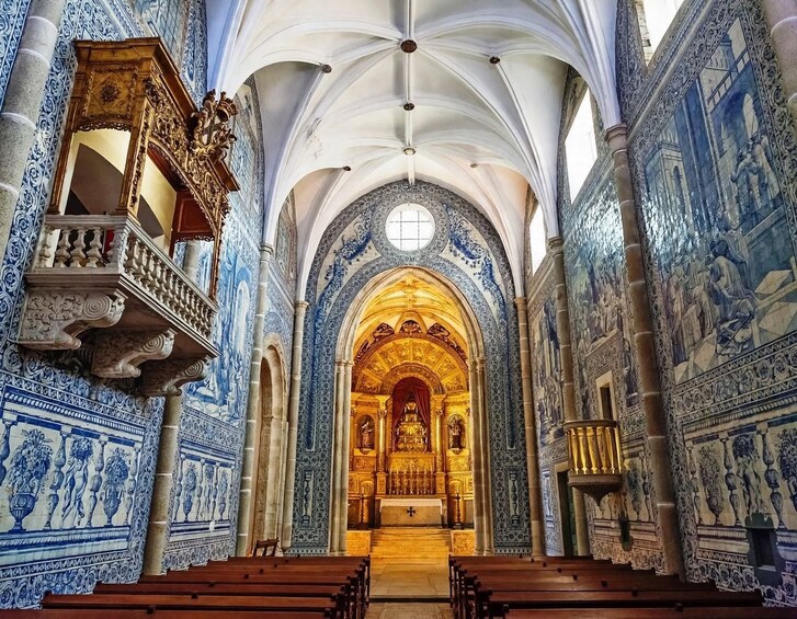 Een kerkinterieur met blauw- en wit betegelde muren, een houten kansel en een gouden altaar. 4