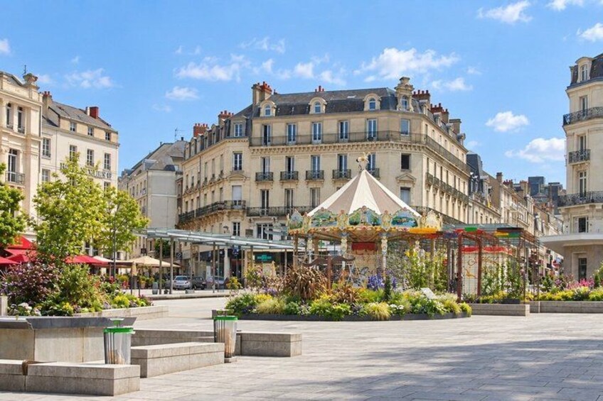 A European square with a carousel, buildings, and a clear sky. 5