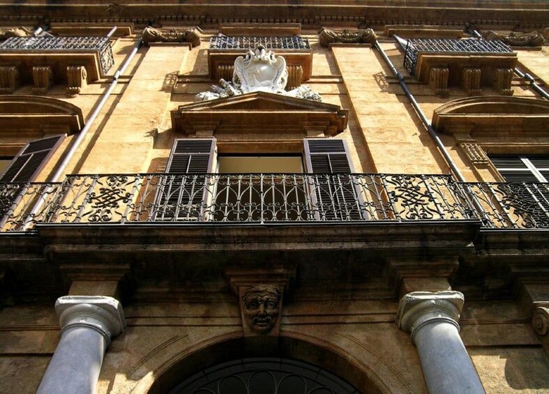 A building facade with ornate balconies, columns, and a central decorative element. 1