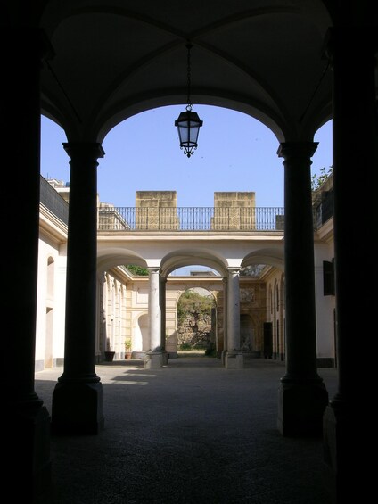 An open courtyard with a covered walkway, columns, and a hanging lantern. 3