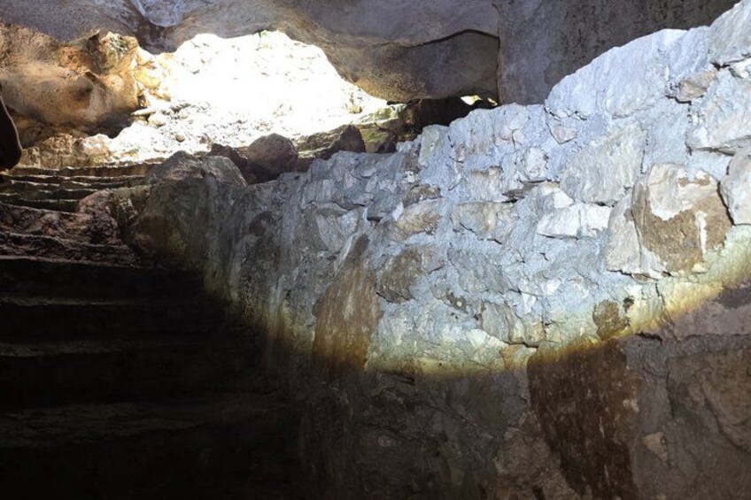 A cave interior with rock formations and a light source illuminating the area. 4