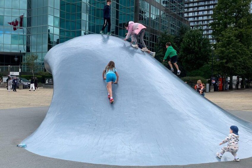 A large, curved concrete structure with people climbing and sliding down. 2
