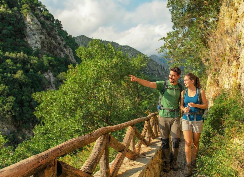 Two hikers on a wooden trail with a mountainous landscape in the background. 1
