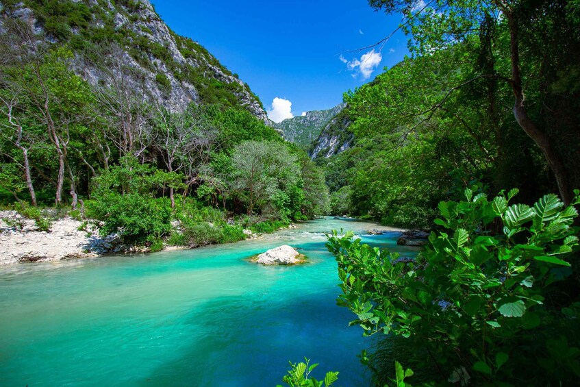 A turquoise river flowing through a forested valley with rocky cliffs and dense greenery. 4