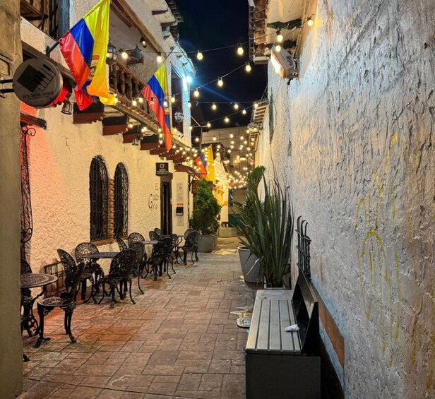 An outdoor café with tables and chairs, string lights, and flags. 2