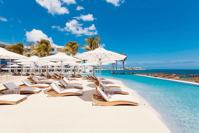 A beach resort with white umbrellas and lounge chairs. 4