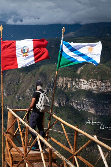 Una persona en una escalera de madera, con banderas de Perú y Chile al fondo. 2