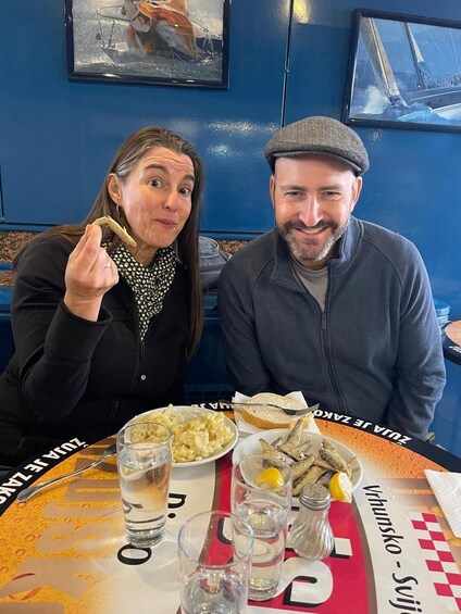 Two people sitting at a table with food and drinks. 2