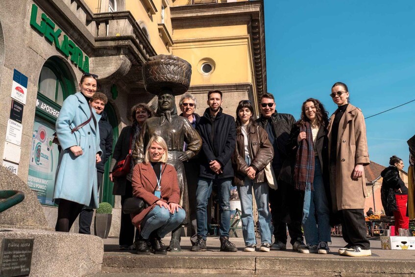 A group of people posing in front of a building with a large statue and a sign that reads 'LEUKER'. 3