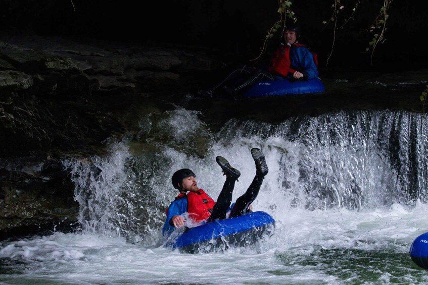 A person in a blue inflatable tube being tossed into a waterfall. 1
