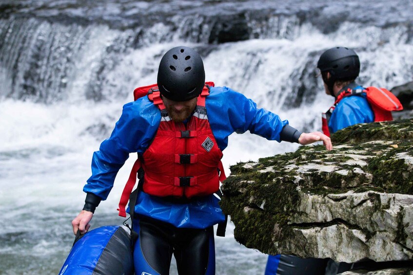 A person in blue and red gear preparing to rappel down a waterfall. 5