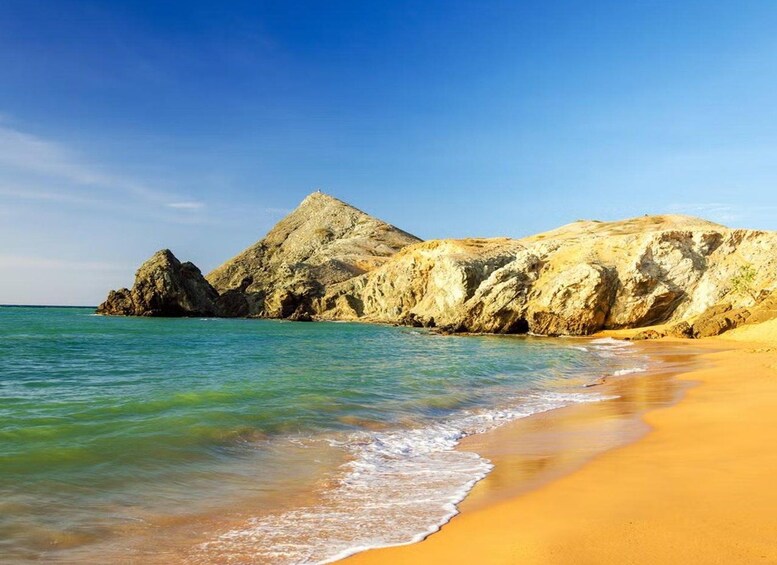 A beach with clear turquoise water, golden sand, and rocky cliffs. 1