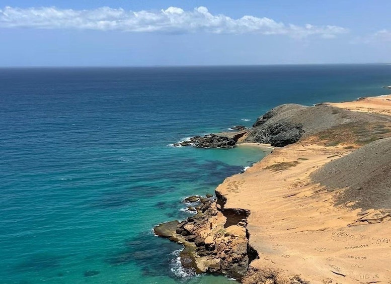 A coastal landscape with clear blue waters, sandy beaches, and rocky outcrops. 4