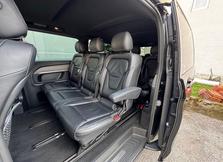 A vehicle interior with black leather seats, a central console, and a rear view mirror. 2