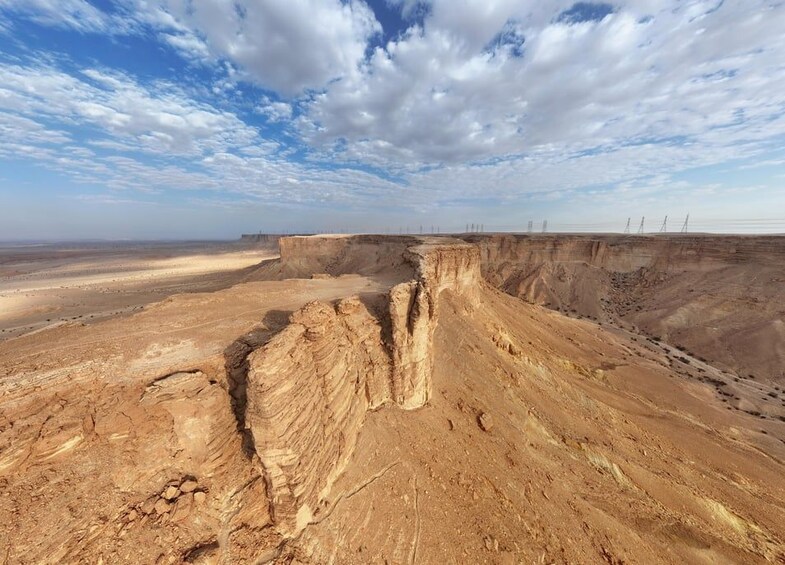 Un extenso paisaje desértico con un profundo cañón y líneas eléctricas a lo lejos. 5