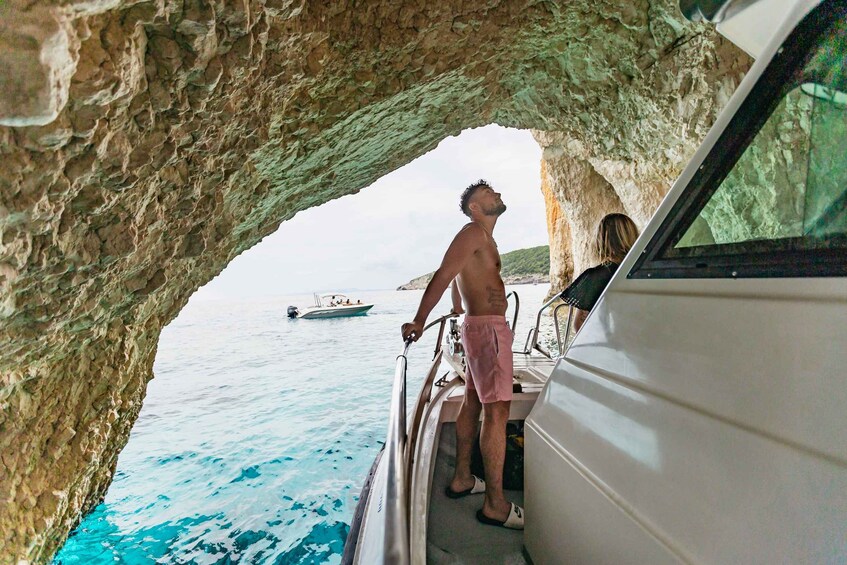 Un homme se tient sur le pont d’un bateau, et observe la mer à travers l’ouverture d’une grotte rocheuse. 5
