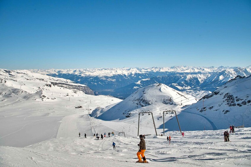 A snowy mountain landscape with skiers and a ski lift. 1