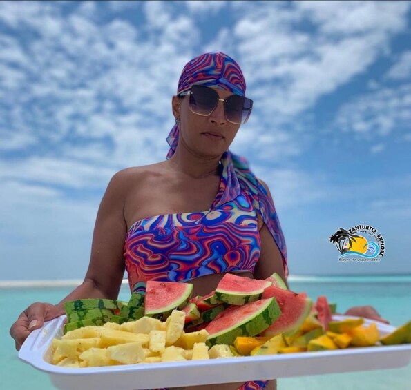 Una persona sostiene una bandeja con sandía y fruta en la playa. 4
