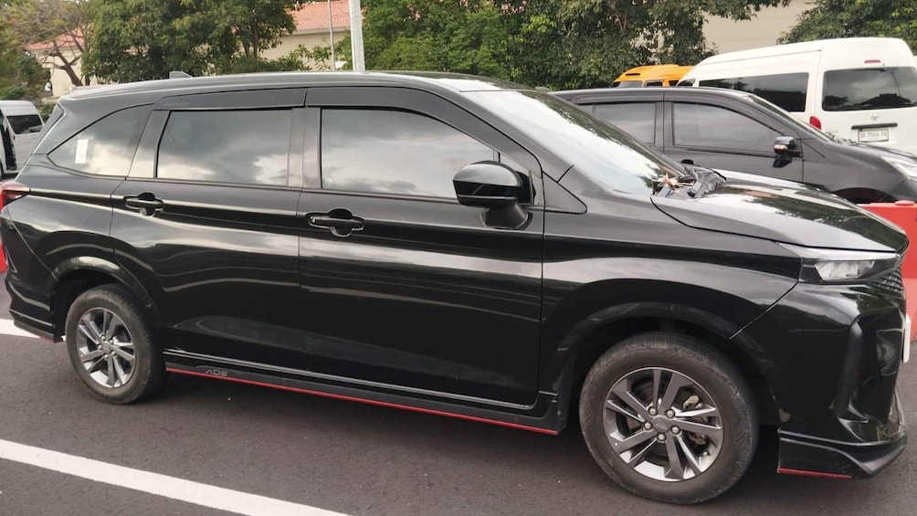 A black SUV parked on a street with a red stripe along the side. 2
