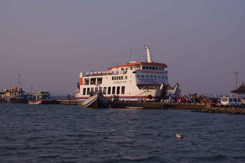 A large ferry docked at a pier with several smaller boats nearby. 3