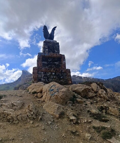 A stone monument with an eagle sculpture on a rocky hilltop. 3