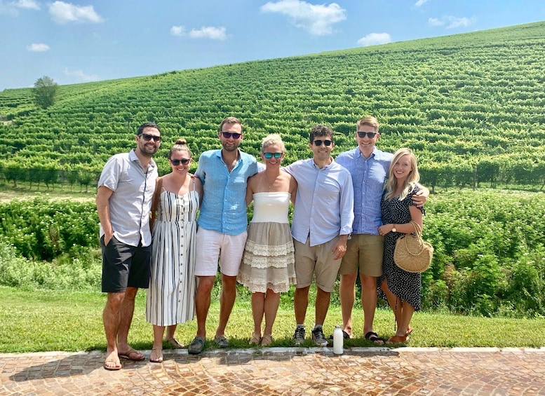 A group of people standing in a vineyard with rows of grapevines. 4