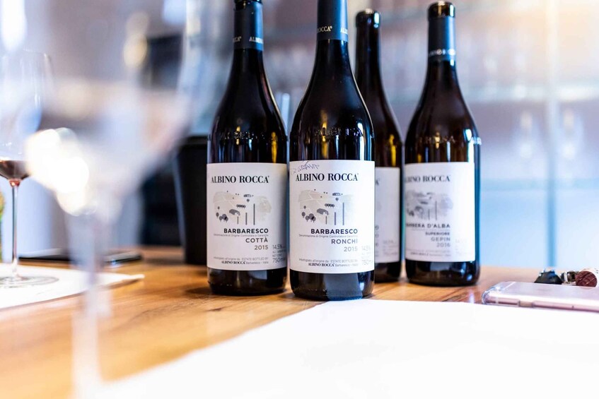 Three bottles of Albino Roccata wine on a wooden table. 3