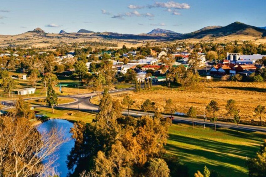 A rural landscape with a winding road, a small town, and distant mountains. 2