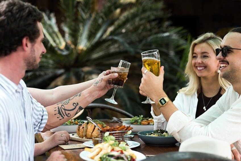 A group of people toasting with drinks at a table with food and a basket of bread. 4
