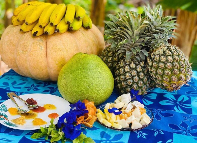 A table with a variety of tropical fruits including a pumpkin, pineapple, guava, and a plate with a spoon and some fruit pieces. 4