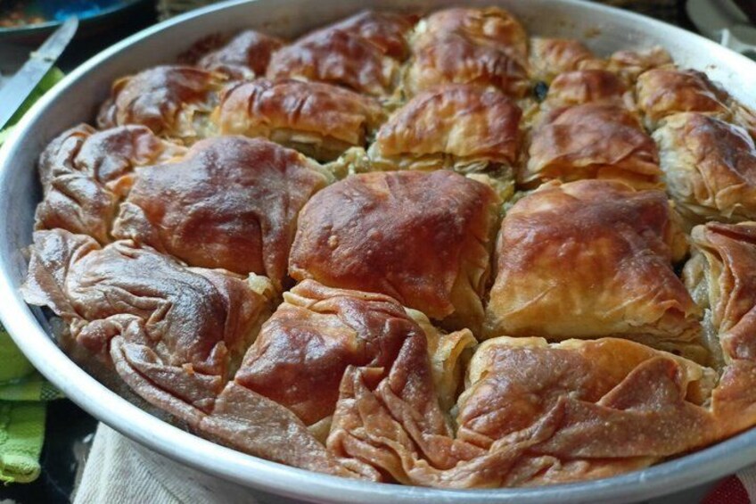 A tray of baked pastries, likely spanakopita, arranged in a circular pattern. 1