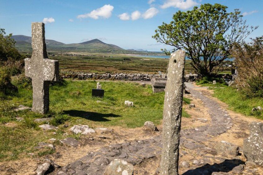 A rural landscape with a stone cross, a path, and a distant mountain. 3